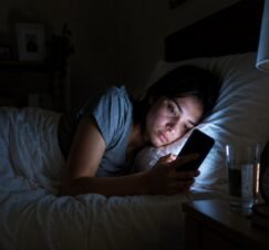Woman using a phone in bed at night.