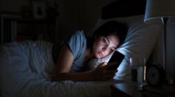 Woman using a phone in bed at night.