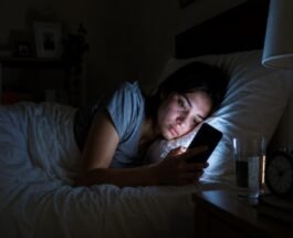 Woman using a phone in bed at night.