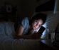Woman using a phone in bed at night.