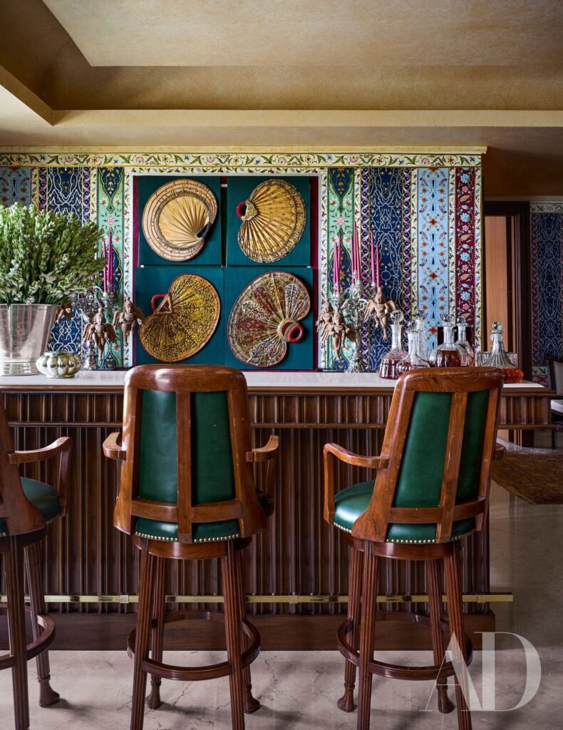 Colorful traditional bar area with patterned tile walls, wooden chairs, decorative fans, and glassware.