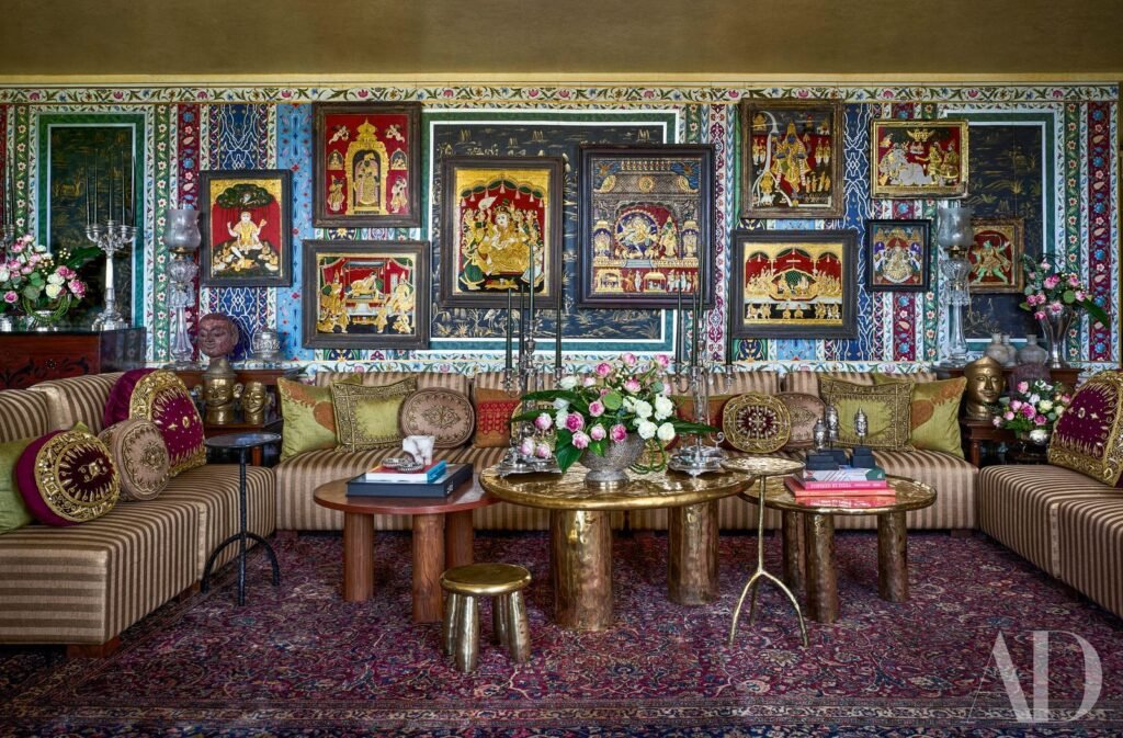 Ornate Indian-inspired living room with colorful artwork, patterned textiles, and gold accents.