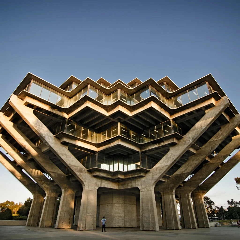 Brutalist modern building with angular concrete terraces and glass windows.